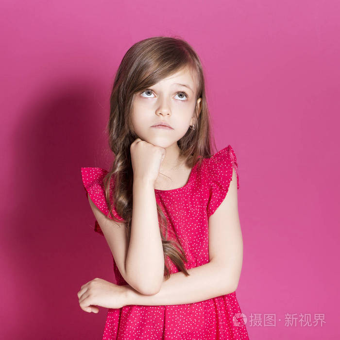 8岁的小女孩在粉红色的中性背景下用手做一些情绪化的手势她有长黑发