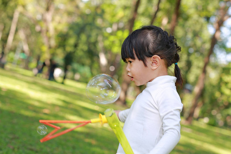 可爱的小女孩玩泡沫在公园里