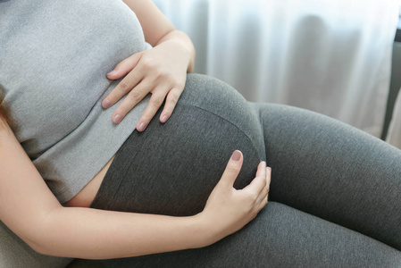 产假床怀孕的女人躺在家里床上摸她的肚子照片