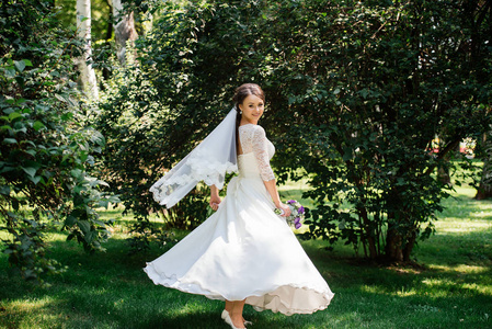 新娘穿着白色的裙子在公园里旋转。衣服在风中发展。幸福的新娘穿着婚纱纺纱