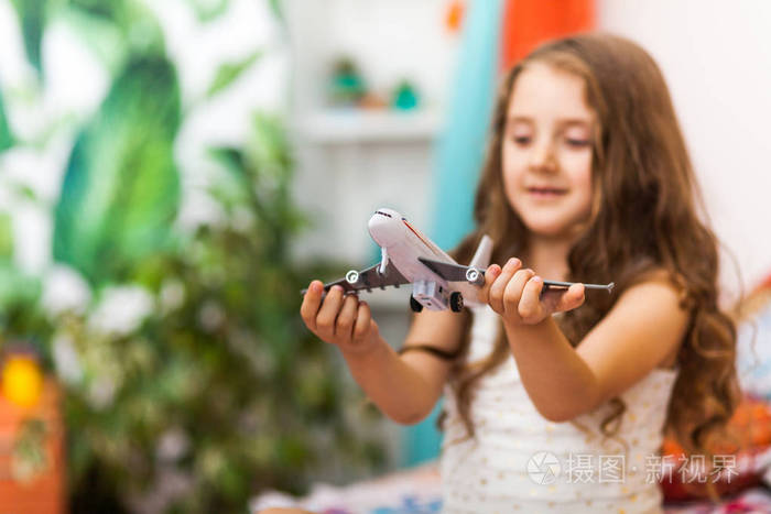 可爱的阿拉伯室内迷人的小女孩拿着一架飞机。旅游理念
