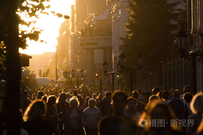 在夏日傍晚的日落时分, 人们漫步在行人区的剪影人群