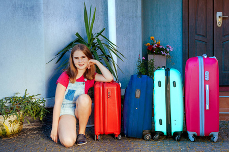 一个女孩和一个大的拉布拉多狗在多色的手提箱附近。全家为暑假的旅行做好了准备。全家与户主之旅