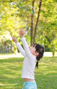 可爱的小女孩玩泡沫在公园里