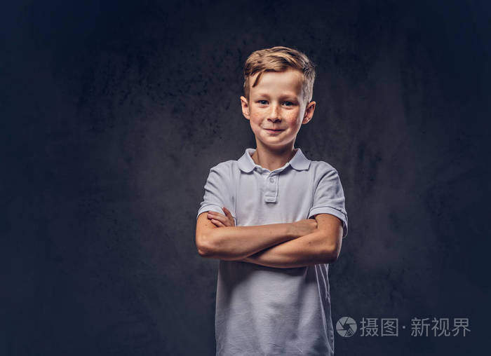 可爱的小男孩穿着白色t恤站在工作室交叉手臂在深色纹理背景下隔离