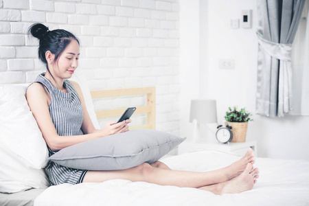 妇女休息和放松在床上使用手机设备. 生活方式和在家工作的概念