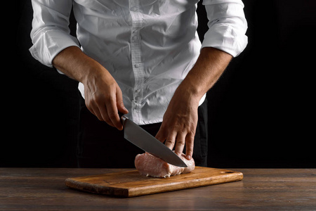厨师把一块新鲜的肉放在木板上, 靠在深色的背景上, 手特写。烹调, 烹调肉, 肉菜食谱的概念