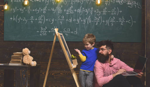 学生与老师在学校。父亲和儿子学习新的知识和技能。孩子指着黑板, 而拥抱坐在爸爸的脖子上