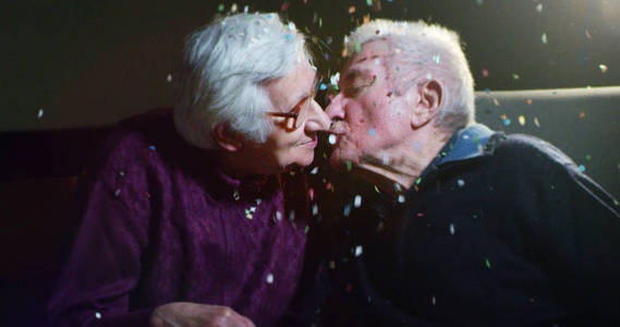 老两口温柔地在 90 生日玩五彩纸屑和在慢动作中接吻