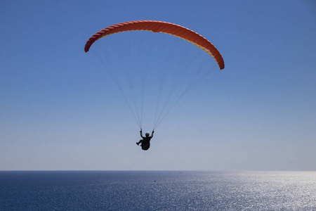 一个勇敢的人在一个阳光明媚的日子, 在开阔的海面上飞翔在滑翔伞上。海滨度假胜地的旅游景点
