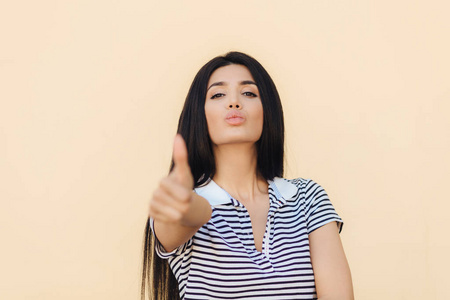 圆表情自信快乐的年轻女子带着自信的表情, 不停地举起大拇指, 表现出