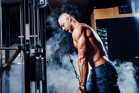英俊的肌肉健身健美运动员的肱三头肌在健身房里锻炼重