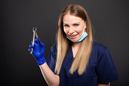 女牙医戴口罩和戴乳胶手套的牙医指着女性病人附近的牙齿模型专业牙科