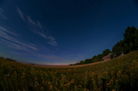 在广阔的田野和一座小乡村小屋的星空. 晚上的照片.