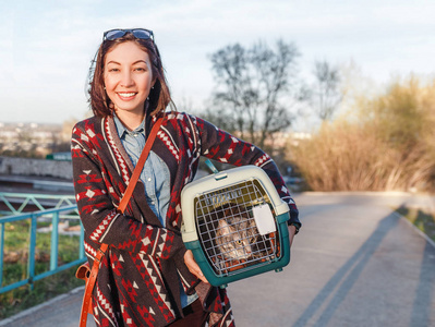 一名妇女正在将一只猫运送到一个特殊的塑料笼子里, 或者把袋子送到兽医诊所。