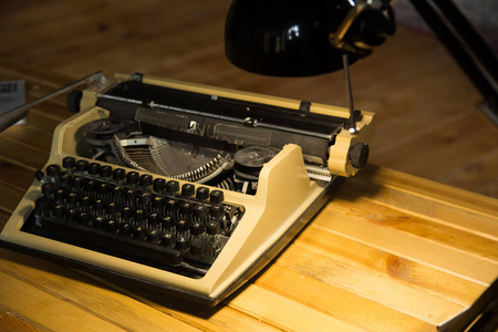用木制漆桌上的灯照亮的旧打字机