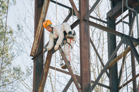 穿着制服的工业登山者和在户外高度工作的头盔。职业工人在水塔上冒险工作