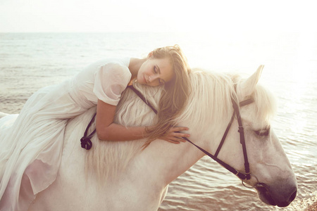 马在海滩上白色连衣裙的女孩
