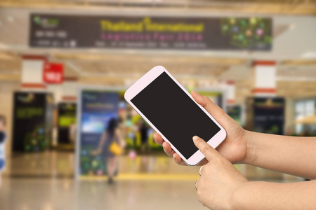 女性手在模糊的商店背景使用智能手机
