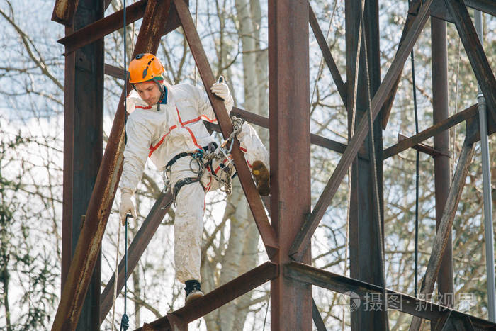 穿着制服的工业登山者和在户外高度工作的头盔。职业工人在水塔上冒险工作