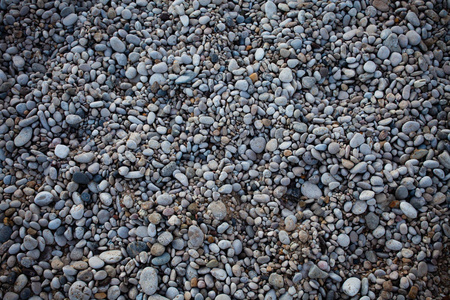 小沙滩轻卵石岩地板。不同的石头背景纹理的性质。户外。有多个形状的栅格砾石。自然形成。颜色灰色