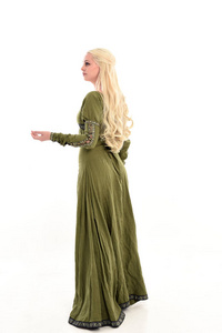 身穿绿色中世纪长袍的金发女郎的全长肖像。站姿面对远离相机, 孤立的白色演播室背景