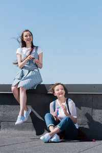 两个微笑的女性朋友用气泡鼓风机在屋顶上