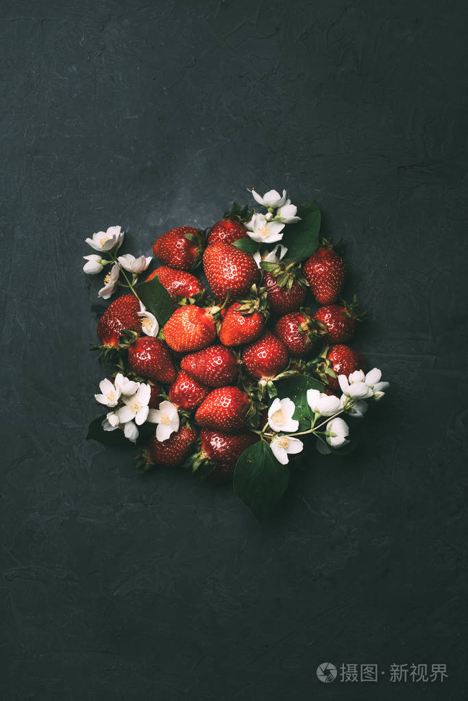 新鲜成熟的草莓和茉莉花在黑色的顶部视图