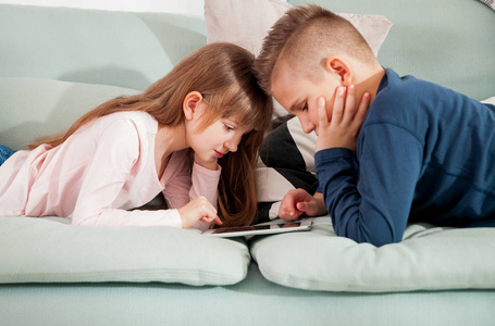 青春期男孩和女孩在沙发上玩平板电脑