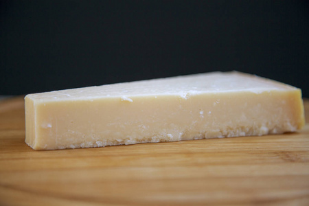 一块在木板上的干酪干酪。特写。侧面视图