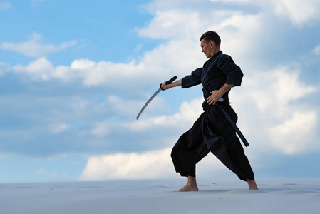 是练习日本武术-iaido 在沙漠中用日本剑-一个武士刀在日落的背景下