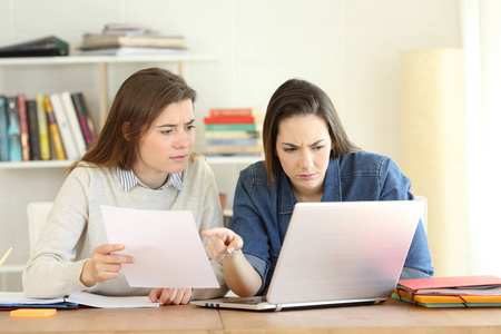 两名集中学生在家里用笔记本电脑比较纸质文件