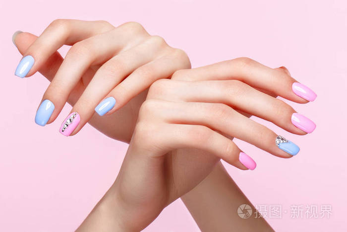 美丽的粉红色和蓝色的指甲与水晶女性手。特写