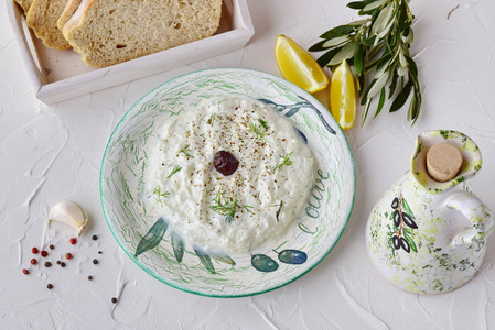 希腊传统酱酸奶汁黄瓜 大蒜 酸奶和柠檬在碗 罐和橄榄油对抽象的背景。健康饮食的概念。地中海的生活方式