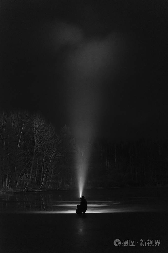 晚上在森林里站在户外的人用手电筒闪亮向前.漂亮的强光束.