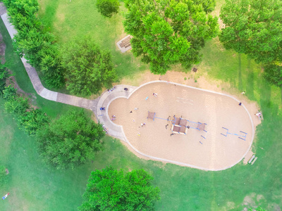 在得克萨斯州休斯顿 Harwin 公园的一个大孩子游戏游乐场的鸟瞰图。在公园四周绿树环绕的幻灯片和秋千的高视图。儿童户外游乐和娱