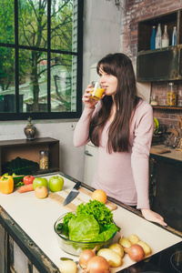 女人在厨房里拿着一杯橙汁。健康饮食的概念。饮食