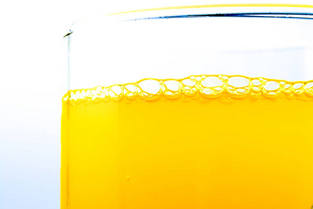 泡沫橙汽水在玻璃特写宏观纹理背景。明亮的风景照片