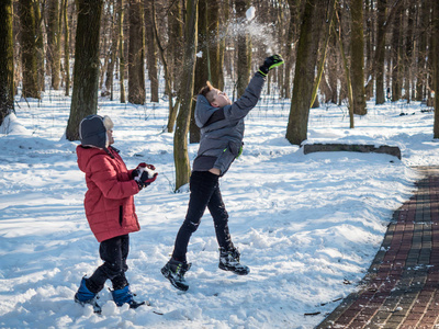 二个小男孩投掷雪和在冬天公园乐趣