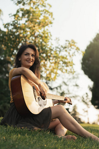 hermosa mujer tocando la guitarra en el parque美丽的女人，在公园里的吉他