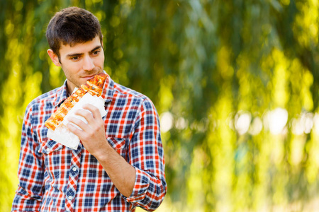 一个年轻男子吃比萨饼的肖像。产品演示徽标和文本的样机。生活方式