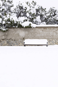 在公园旁边一条雪的街道上充满了积雪的孤独的木凳