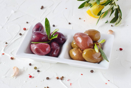 白板用黑色和绿色橄榄橄榄叶上白色的抽象背景与柠檬 樱桃番茄 香料。健康的食物。希腊的食品。地中海食物