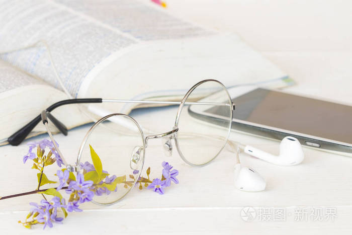 眼镜与书字典英语和移动电话为学生在桌白色的研究