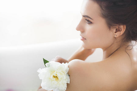 花和牛奶沐浴的年轻美丽的妇女照片