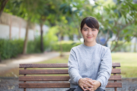 幸福的女人坐在公园的板凳上