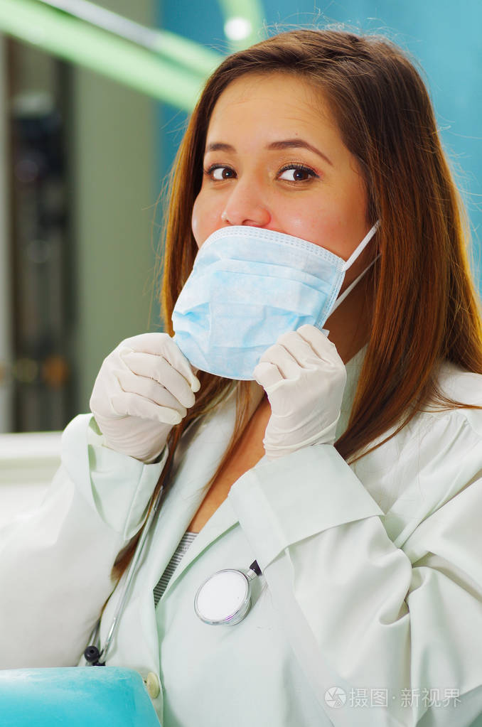 美丽的女医生在牙医的办公室,使用手术口罩