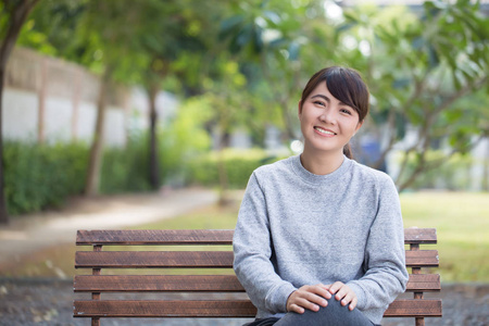 幸福的女人坐在公园的板凳上