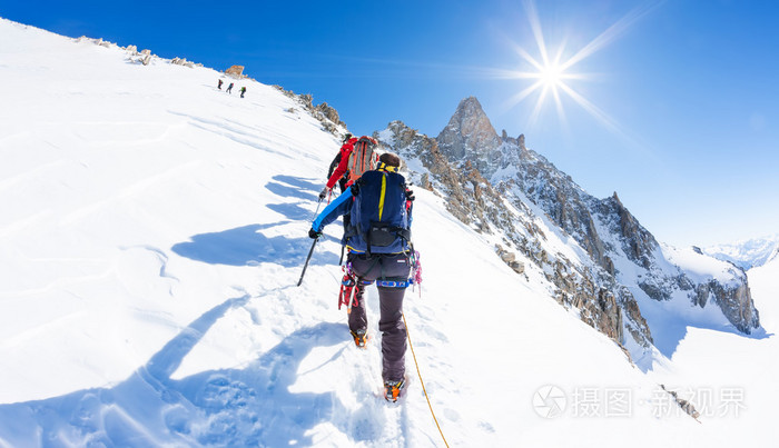 登山者攀登雪峰.在背景著名高峰 d