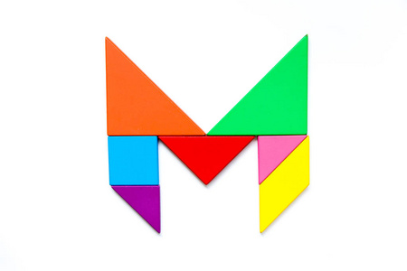 白色背景下英文字母 m 形状的彩色七巧板拼图照片